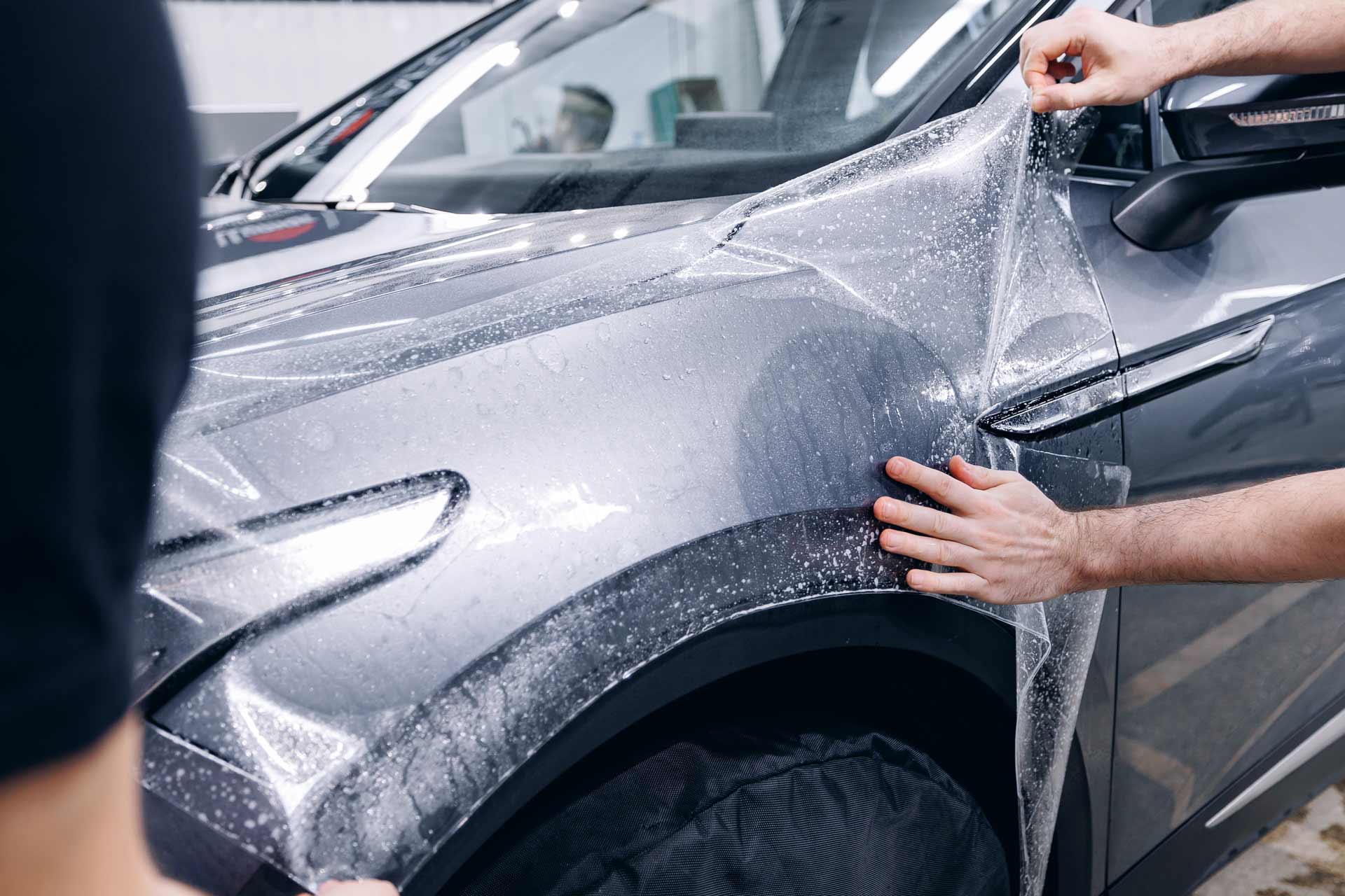 Paint protection film being installed on a grey SUV