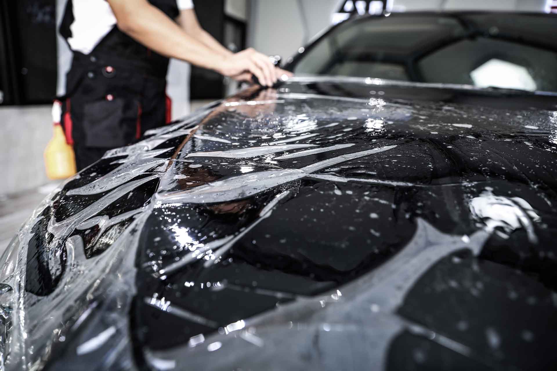 Paint Protection Film being applied to a black luxury car